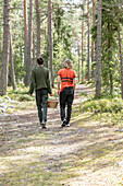 Zwei Jungen (14-15, 16-17) beim Beerensammeln im Wald, Rückansicht