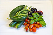 Fresh tomatoes, cucumber, courgette and green peas on white background