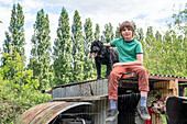 Boy (12-13) and dog sitting on shack roof