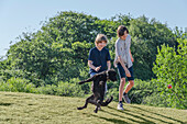 Zwei Jungen (12-13) und Hund spielen auf einer Wiese