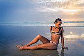 Junge Frau im Bikini am Tallows Beach bei Sonnenaufgang; Neusüdwales, Australien