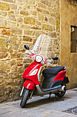 A Motor Scooter Parked Beside A Stone Wall; Barcelona, Spain