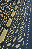 An Ornate Metal Fence And It's Shadow On The Ground; Hamburg, Germany