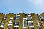 Brick Residential Buildings With Pipes Going Up The Wall And Antenna On The Roof; London, England