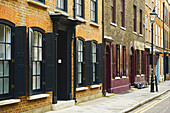 Bemalte offene Fensterläden an Fenstern von Backsteingebäuden, Spitalfields; London, England.