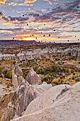 Abundance Of Hot Air Balloons Flying Over The Rugged Landscape Of Honey Valley At Sunset; Cappadocia, Turkey