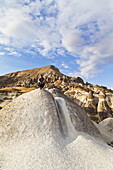 A Man Crouches On A Large Rock In A Landscape Of Fairy Chimneys; Cappadocia, Turkey