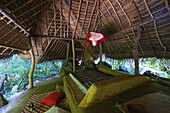 Ein Bett in einem Unterstand mit schrägem Dach; Ulpotha, Embogama, Sri Lanka.
