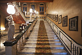 Staircase With Photographs Lining The Wall And Statues On The Railing In Falaknuma Palace; Hyderabad, Andhra Pradesh, India