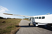 Ein weißes Flugzeug sitzt auf einer Landebahn in einem abgelegenen Gebiet; Vamizi Island, Mosambik