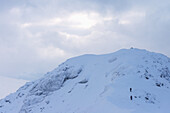 Zwei Menschen nähern sich dem Gipfel des Beinn Dorain bei verschneiten, winterlichen Bedingungen, nahe Bridge Of Orchy; Argyll und Bute, Schottland.