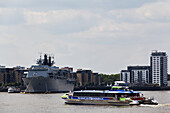 Blick auf die Themse, ein Pendlerboot von Transport For London und die in Greenwich angedockte Hms Ocean; London, England.