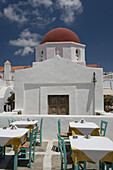 Taverna-Tische vor einer Kirche; Mykonos-Stadt, Mykonos, Kykladen, Griechische Inseln, Griechenland