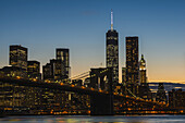 Lower Manhattan in der Dämmerung mit der Brooklyn Bridge; New York City, New York, Vereinigte Staaten von Amerika