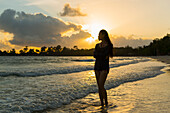 A Young Woman Stands Posing On Sokha Beach At Sunset; Sihanoukville, Cambodia