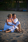 A Couple Sitting On The Beach At The Empire Hotel And Country Club; Bandar Seri Begawan, Brunei