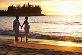 Ein Paar spaziert am Strand bei Sonnenuntergang im Empire Hotel und Country Club; Bandar Seri Begawan, Brunei