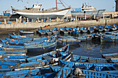 Hafen von Essaouira mit blauen Booten und Fischern, die frischen Fang verpacken; Essaouira, Marokko