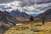 Hikers Walking Along A Ridge In Tombstone Territorial Park In Autumn, With Tombstone Valley And Tombstone Mountain In The Distance; Yukon, Canada