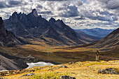 Hiker Standing On An Overlook Taking Photos Of The Colourful Valleys In Tombstone Territorial Park In Autumn; Yukon, Canada