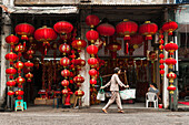 A Chinese Lantern Shop, A Woman Carrying Two Bags With The Traditional Bamboo On Her Shoulder; Xiamen, Fujian Province, China