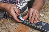 Mann schnitzt ein traditionelles Toraja-Muster auf ein Holzstück, Kete Kesu, Toraja-Land, Süd-Sulawesi, Indonesien