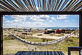Eine Hängematte hängt unter einer schattigen Veranda mit Häusern entlang der Küste; Cabo Polonio, Uruguay.