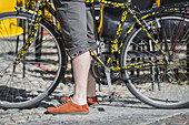 Eine Frau mit orangefarbenen Schuhen steht mit ihrem Fahrrad; Locarno, Tessin, Schweiz