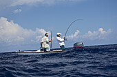 Männer, die von einem kleinen Boot aus einen Fisch fangen; Tahiti