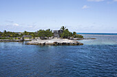 Tropische Insel mit Palmen und einem hölzernen Gebäude und Plätzen für Boote zum Anlegen entlang der Küste; Tahiti
