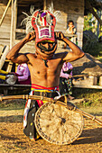 Manggarai-Mann mit traditionellem Kopfschmuck, der mit einem Schild und einer Bambuspeitsche in einem Caci, einem rituellen Peitschenkampf, eingewickelt ist, Dorf Melo, Flores, Ost-Nusa Tenggara, Indonesien