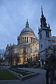 Zwei Menschen gehen in der Abenddämmerung an der St. Paul's Cathedral vorbei; London, England.