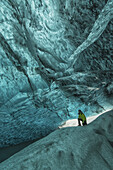 Person, die unter der Vatnajorkull-Eiskappe in einer großen Eishöhle steht, Süd-Zentral-Island; Island