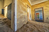 Treibender Sand füllt die Räume eines bunten, verlassenen Hauses; Kolmanskop, Namibia