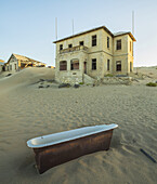 Eine alte Badewanne liegt im Sand vor einem verlassenen Haus; Kolmanskop, Namibia