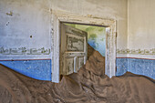 Sand in den Räumen eines farbenfrohen und verlassenen Hauses; Kolmanskop, Namibia