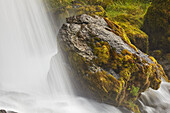 Moosbewachsener Fels und die raue Schönheit des Hafrafell-Wasserfalls in den Bergen bei Stykkisholmur, Halbinsel Snaefellsnes im Westen Islands; Island