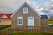 Uriges Haus mit brauner Verkleidung, weißen architektonischen Details und einem hölzernen Lattenzaun; Stykkisholmur, Halbinsel Snaefellsnes, Island.