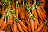 Close up of a basket filled with trimmed bunches of carrots