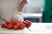 Nahaufnahme eines Arbeiters, der frische Tomaten schneidet
