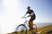 Man cycling on a costal path by the ocean