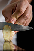 Close up of a chef hand slicing ginger