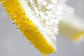 Extreme Nahaufnahme einer Zitronenscheibe, die in kohlensäurehaltigem Wasser schwimmt