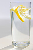 Nahaufnahme eines Glases mit kohlensäurehaltigem Wasser und geschnittener Zitrone
