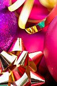 Extreme close up of red and purple Christmas baubles and a gold bow and ribbon