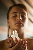 Junge Frau hält einen Kristall in den Händen