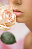 Extreme Nahaufnahme einer jungen Frau, die eine rosa Rose inhaliert