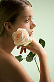 Profil einer jungen Frau, die eine Rose hält