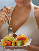 Young woman holding a bowl of fruit salad