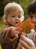 Woman with a child in her arms holding a leaf